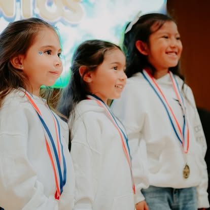 Tres niñas sonriendo con sus medallas