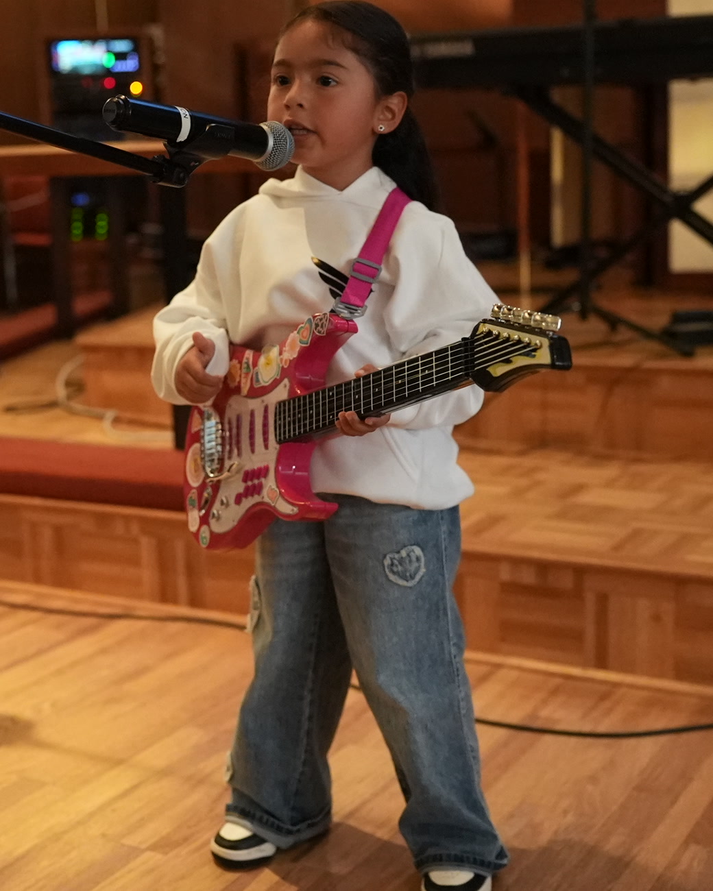 Niña cantando con su guitarra en el servicio